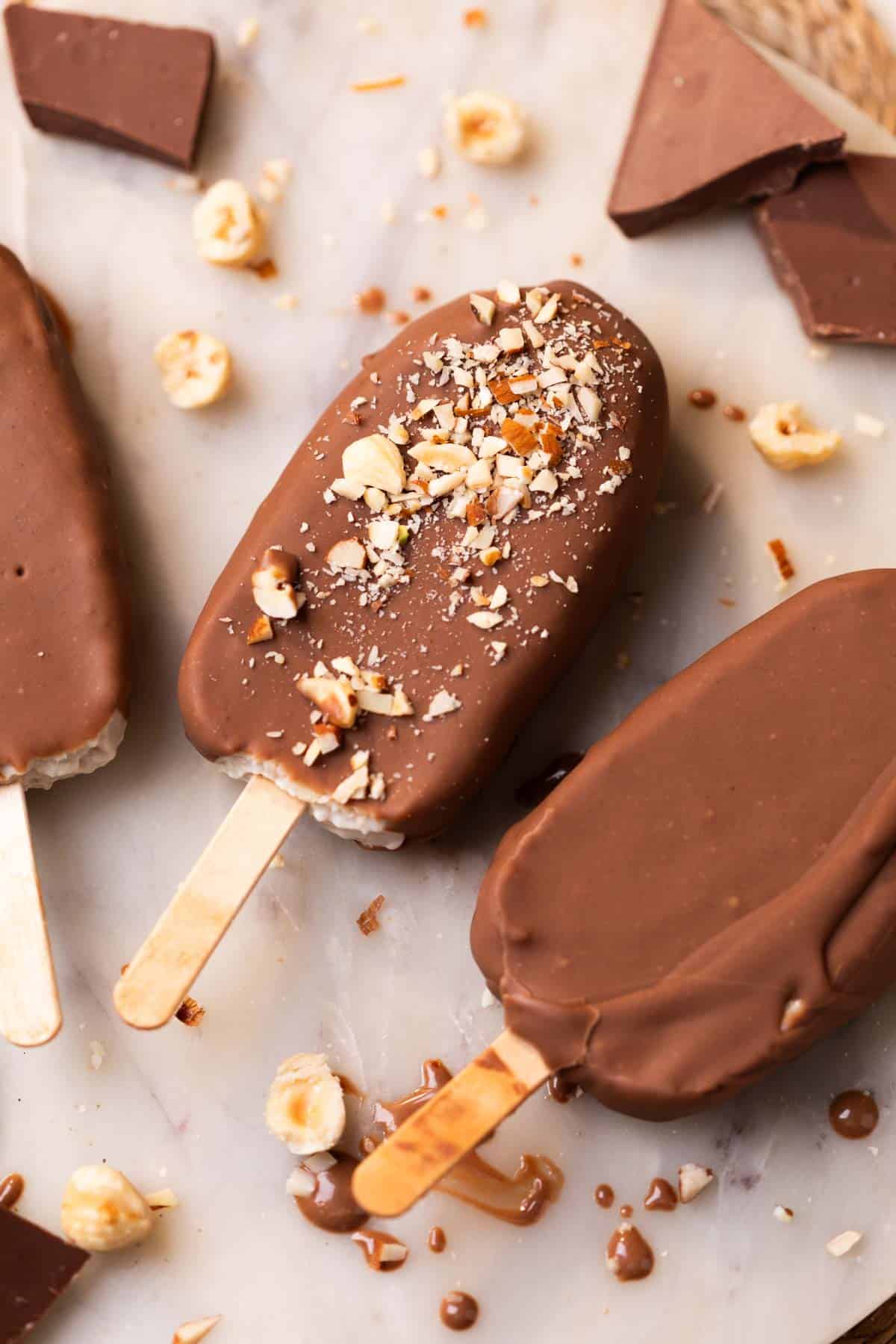 healthy chocobar ice creams garnished with chopped nuts and placed on a white platter