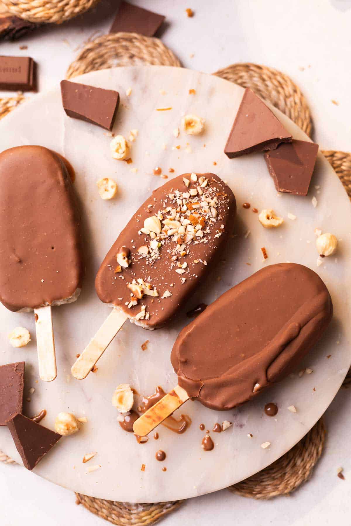 healthy chocobar ice creams garnished with chopped nuts and placed on a white platter