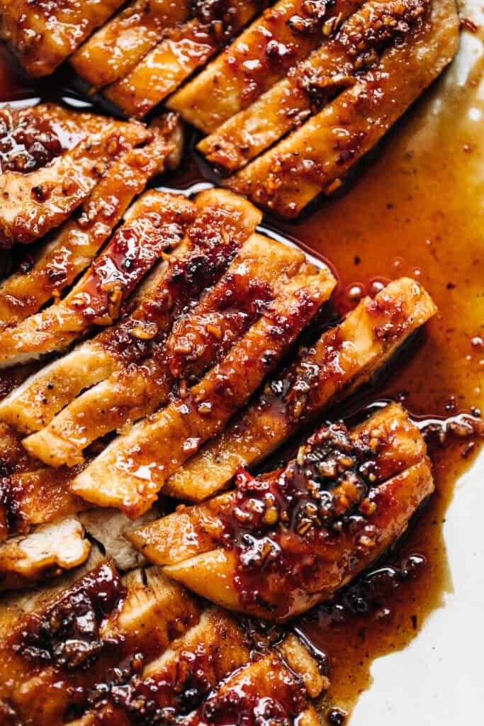 Chicken breast with hot honey butter sauce on a white plate.