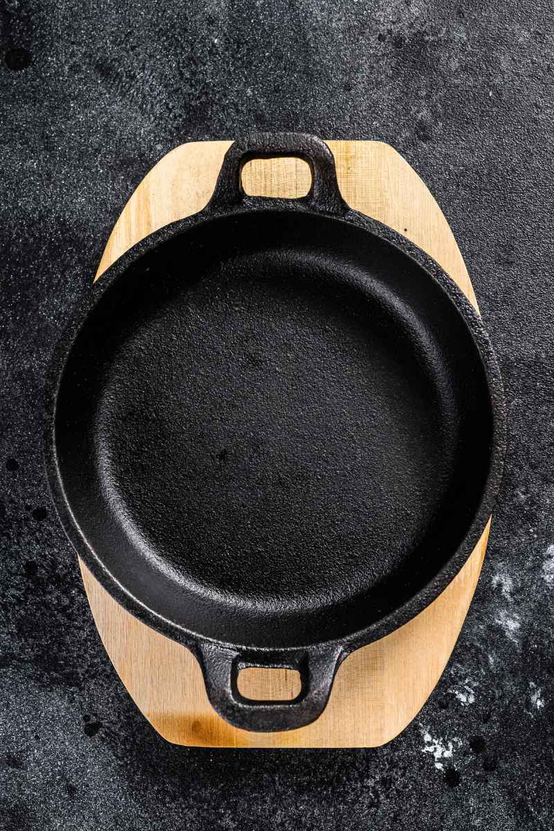 a freshly cleaned and seasoned cast iron pan on a wooden board