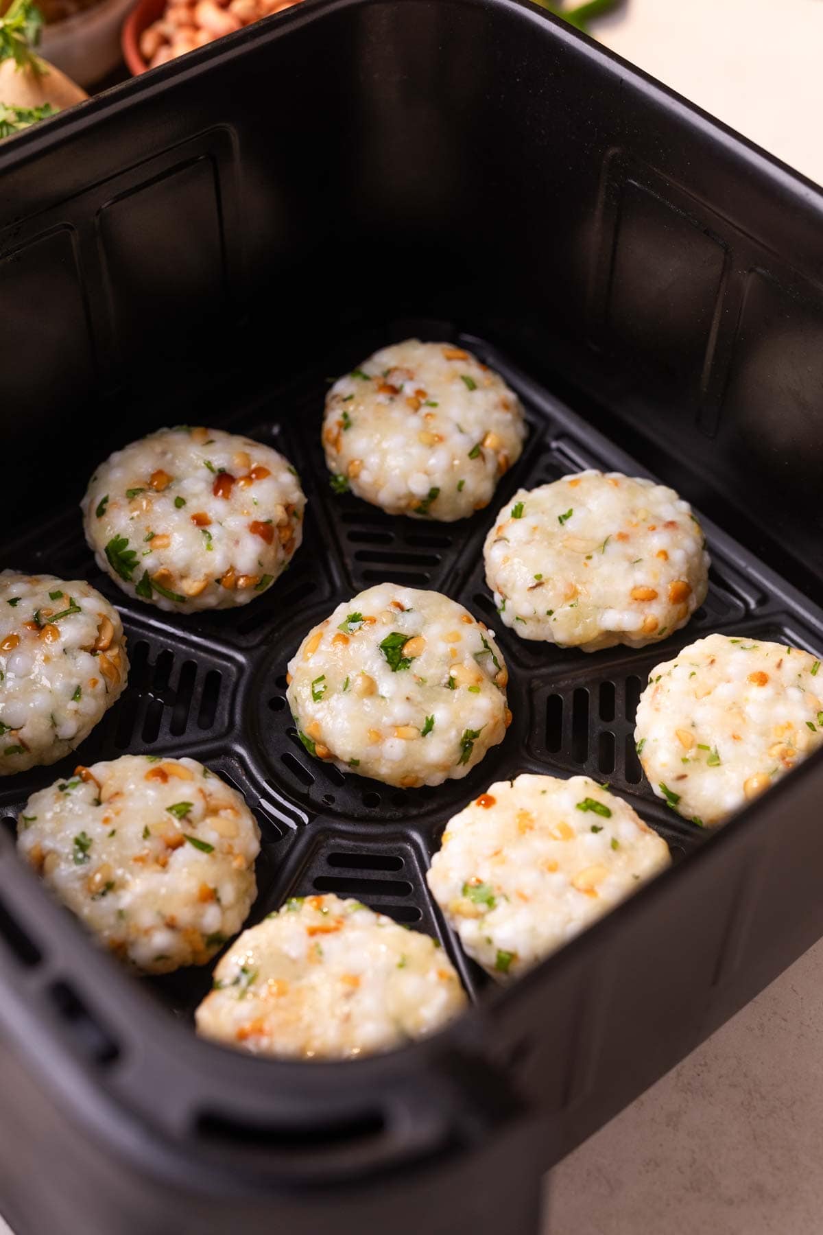 An image of uncooked air fryer sabudana vadas placed in the air fryer ready to bake 