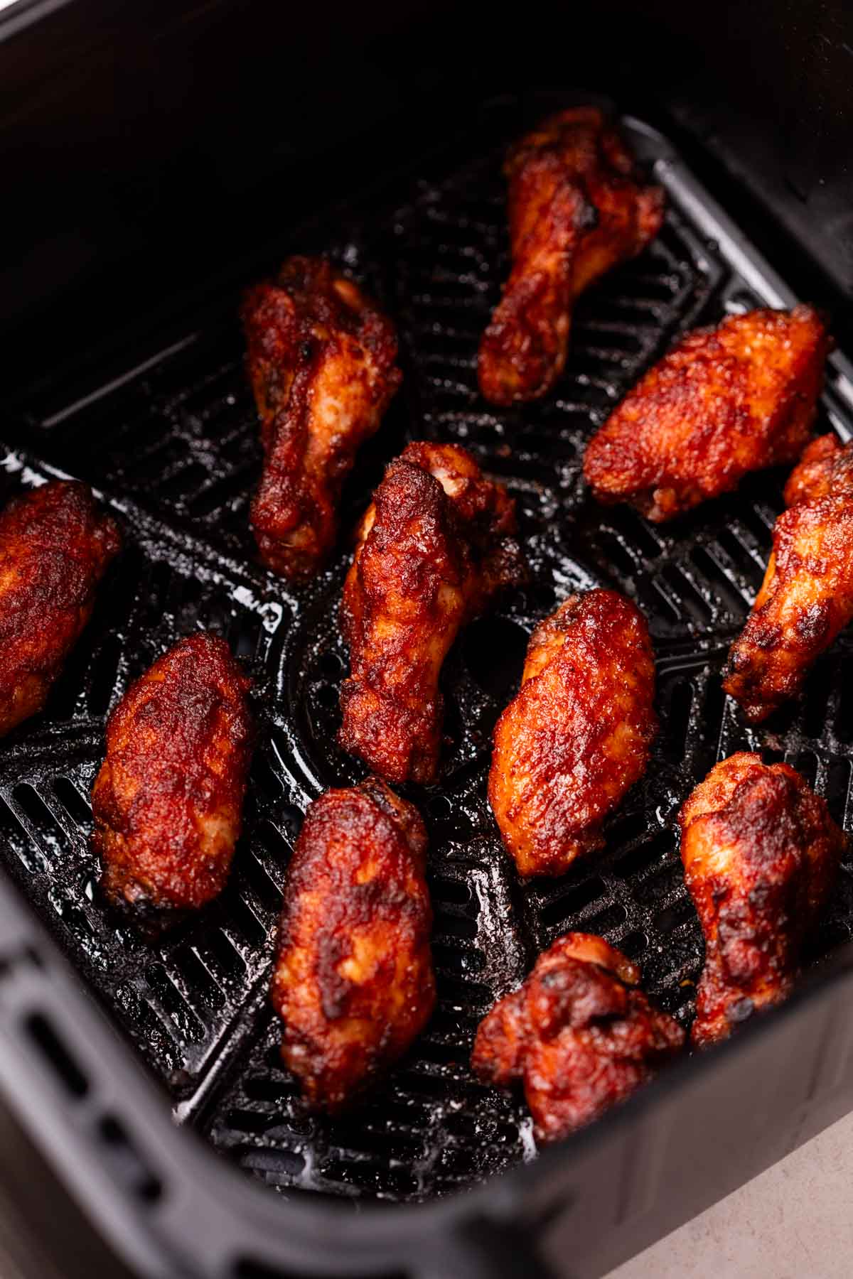 air fryer spicy bbq chicken wings lined in an air fryer basket
