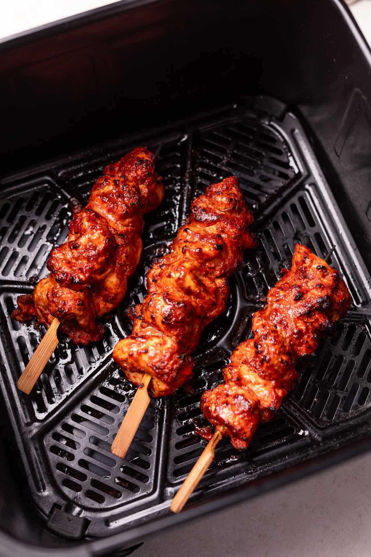 An image of freshly cooked air fryer chicken tikkas still in the air fryer basket