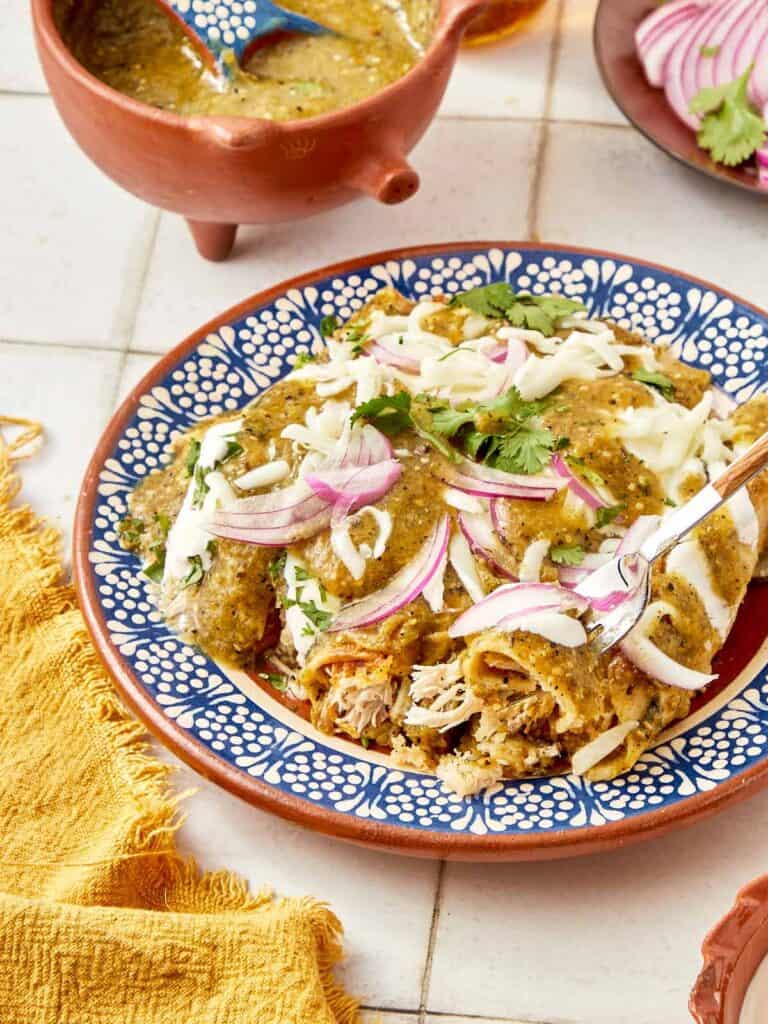 Mexican chicken enchiladas with a blue spoon.