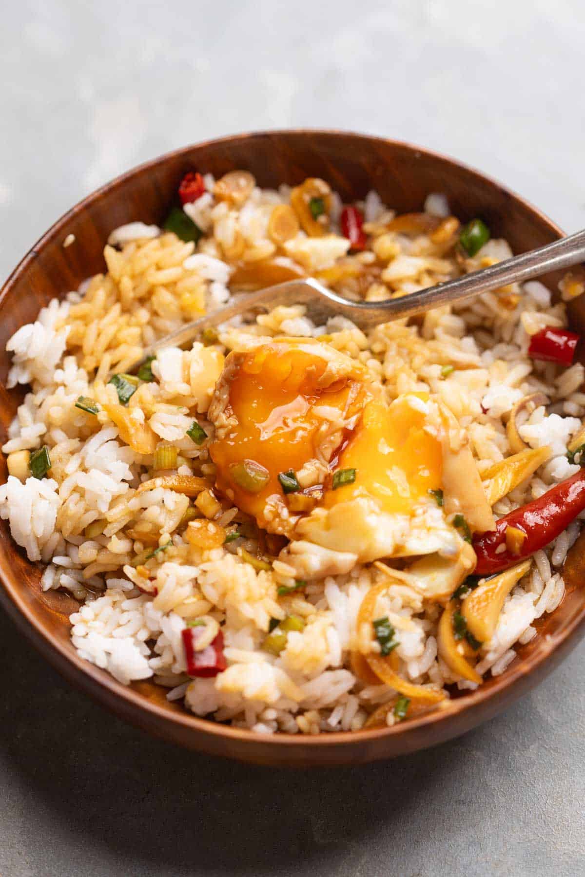 an image of Mayak Eggs poured over steamed rice and served in a wooden bowl with a spoon 