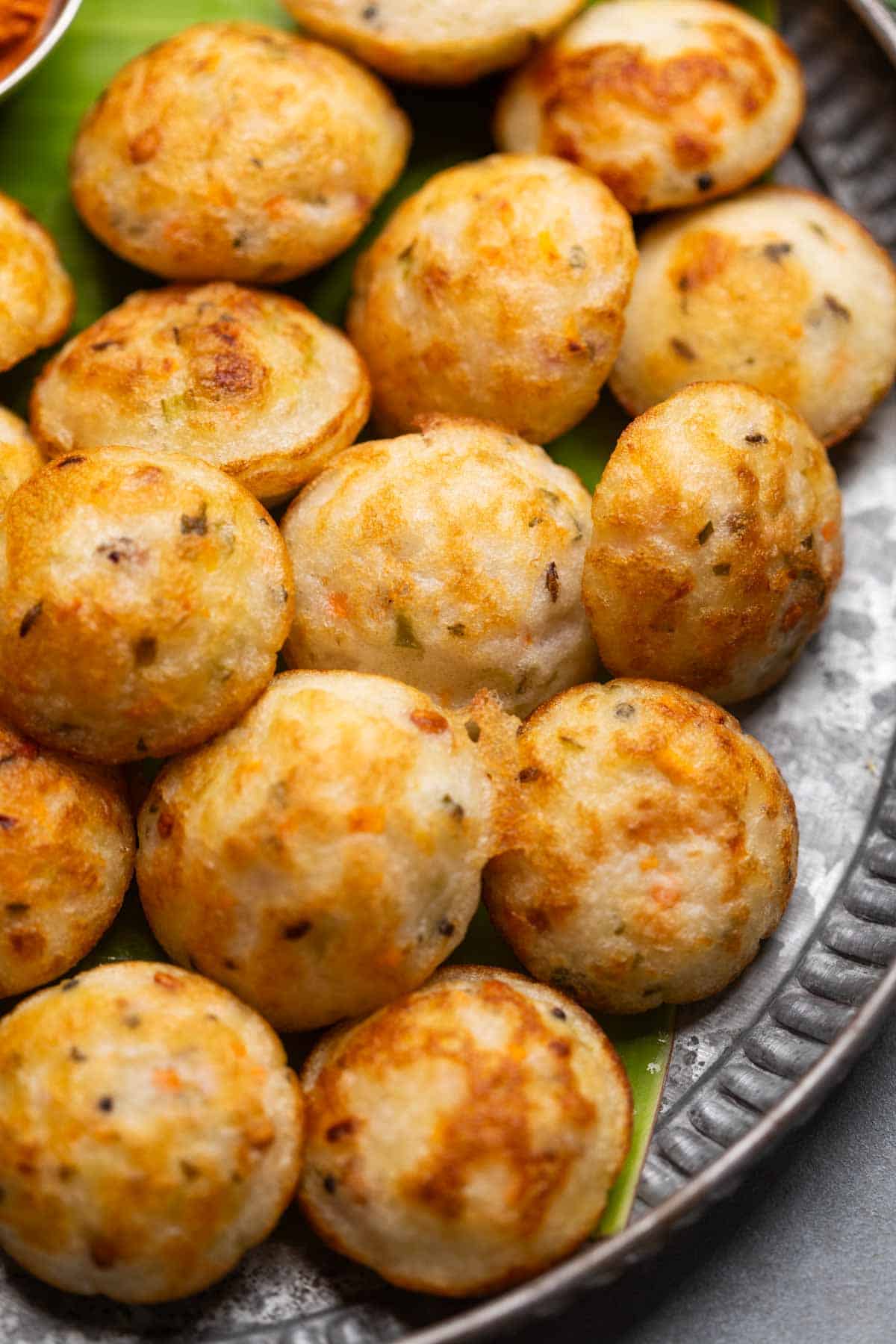 Freshly cooked paniyaram served on a banana leaf platter with accompaniments