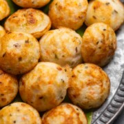 Freshly cooked paniyaram served on a banana leaf platter with accompaniments