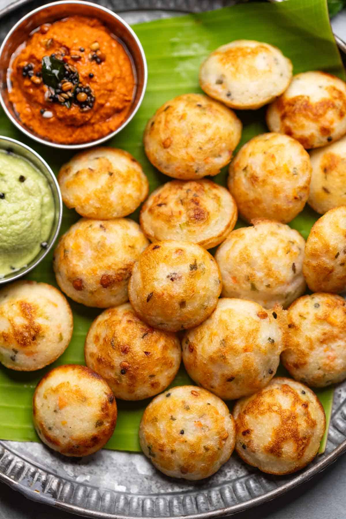 Freshly cooked paniyaram served on a banana leaf platter with accompaniments