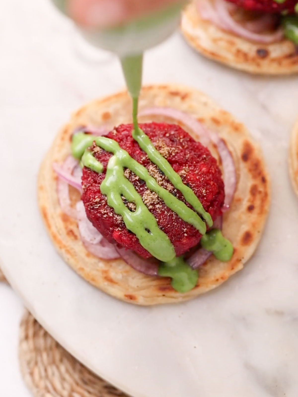 Beetroot tikki served on a flaky paratha with onion rings and garnished with green chutney