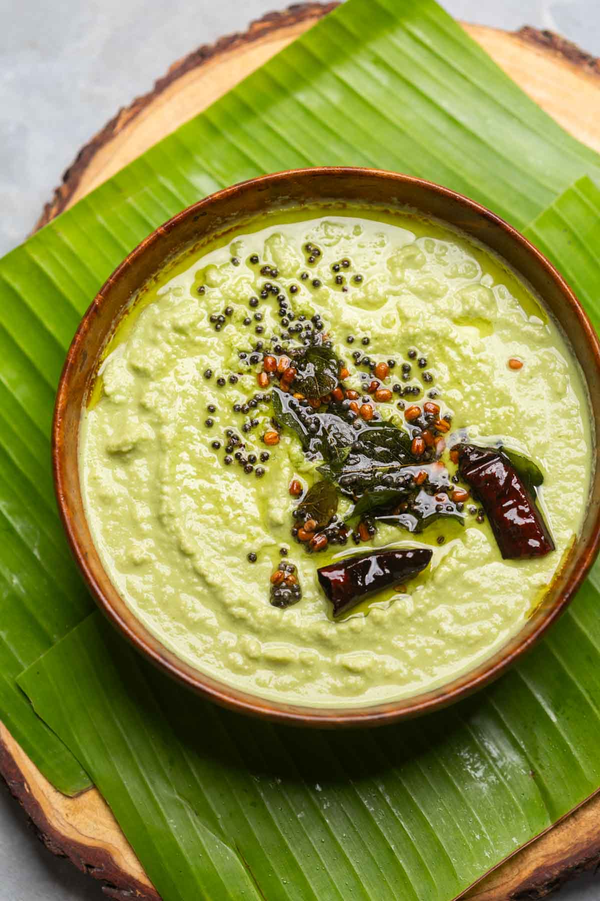 an image of coconut chutney made served in a bowl placed over a banana leaf platter
