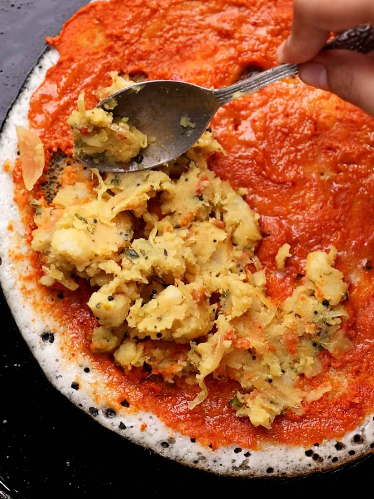 Aloo filling being spread on the dosa