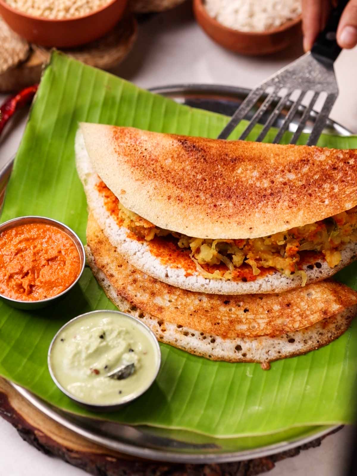Serving mysore masala dosa with two chutneys on a banana leaf