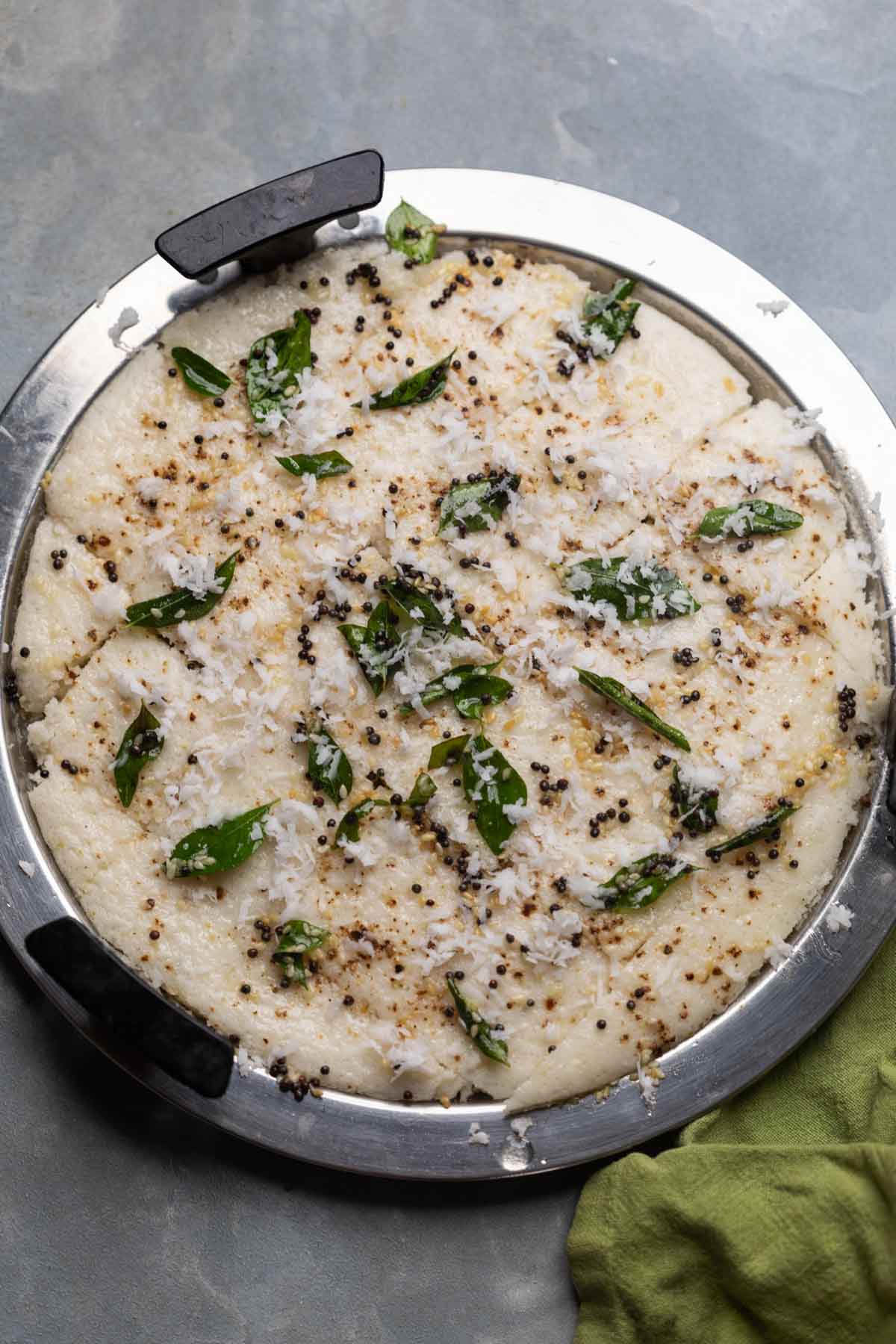 freshly steamed white dhokla still in the steamer plate ready to be served