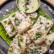 white dhokla served on a banana leaf platter with chutney