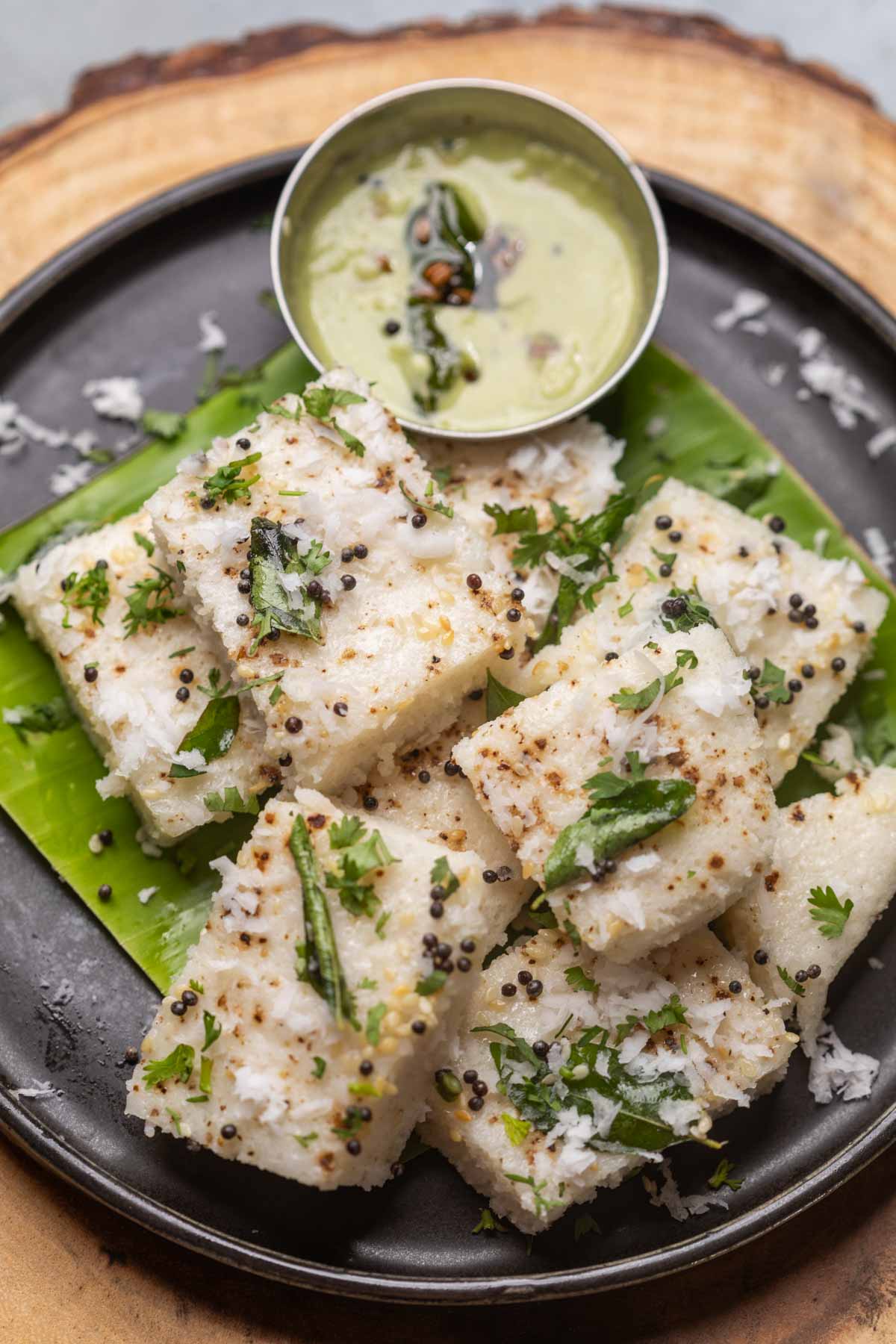 white dhokla served on a banana leaf platter with chutney