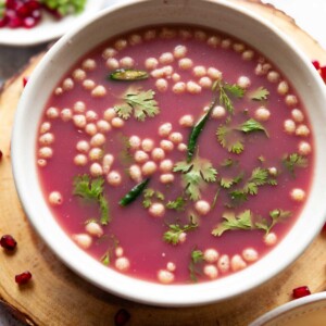 anar pani puri garnished with coriander leaves and boondi and served in a white bowl