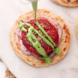 Beetroot tikki served on a flaky paratha with onion rings and garnished with green chutney