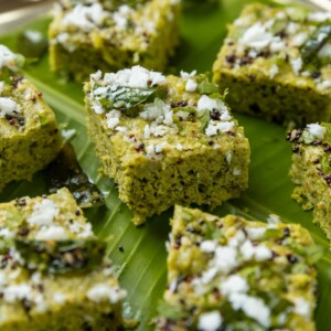 close up of sprouts dhokla garnished with tempering and served on a leaf platter