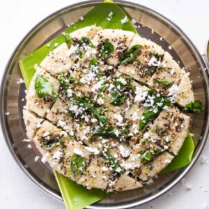 Jowar dhokla served on a banana leaf on a plate with coconut chutney on the side