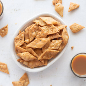 Picture of namak para in a white bowl with cups of chai around it