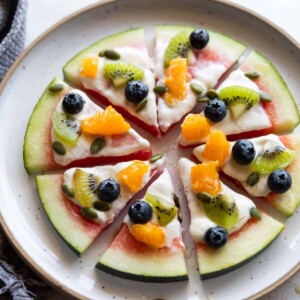 watermelon pizza slices topped with fresh fruits on a white plate