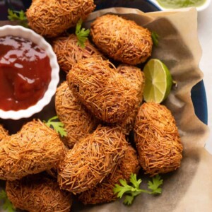 Veg Cutlets served in a blue bowl with green chutney and ketchup