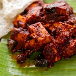 paneer ghee roast served on banana leaf with neer dosa
