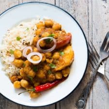 A picture of the curry plated with rice and onions.
