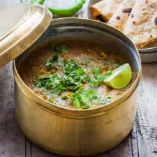 Dhaba Style Dal Fry garnished with lime, coriander and served in a dabba with a side of rotis.
