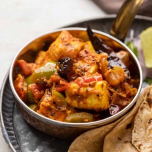 Achari Paneer served in a copper steel bowl with rotis on the side