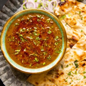 Langar wali dal served in a green ceramic bowl with naan and onions on the side