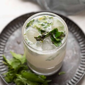 masala chaas with ice cubes served in a glass on a metal tray