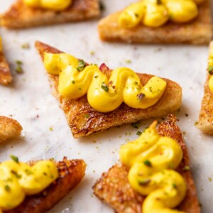 close up of rasmalai sandwich garnished with pistachios and served on a white platter