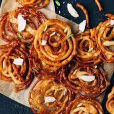 Overhead shot of crispy homemade jalebis with almond flakes sprinkled on top