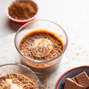 Paneer chocolate pudding topped with whipped cream and cocoa powder in a dessert bowl
