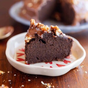 slice of ragi chocolate cake on a white plate with nuts sprinkled on top