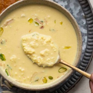 Close up of a spoon of instant rabdi in a brown bowl to show the creamy layers in the rabdi