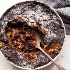 Spoon in a bowl of chocolate pudding cake showing how the sauce is created at the bottom