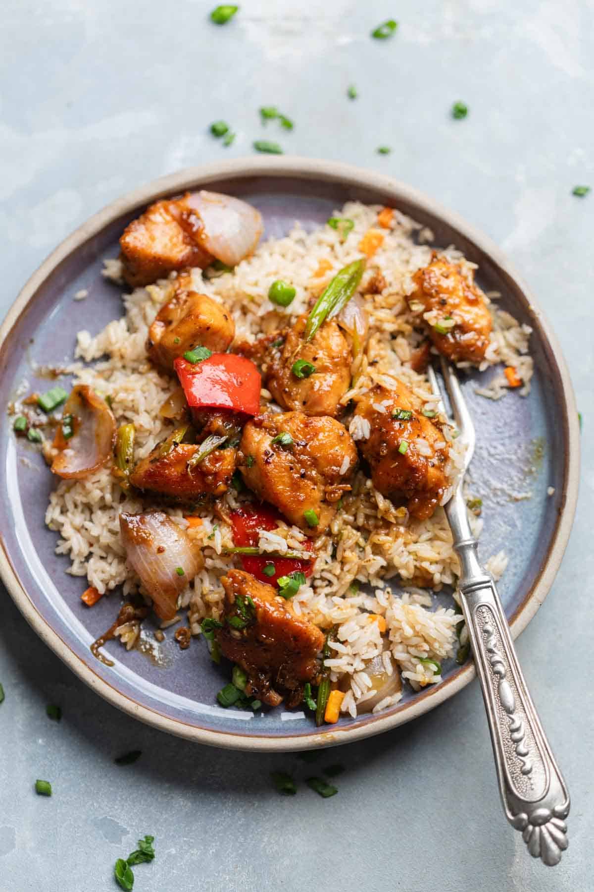 air fryer black pepper chicken poured over rice on a plate