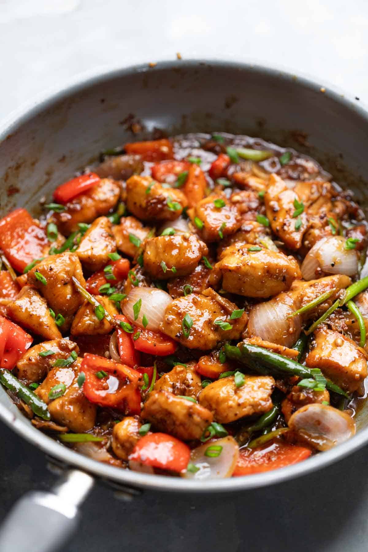 close up of black pepper chicken being cooked in a pan
