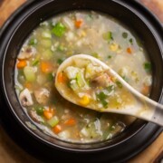 Eight treasure soup served in a black soup bowl with a white soup spoon ready to be eaten