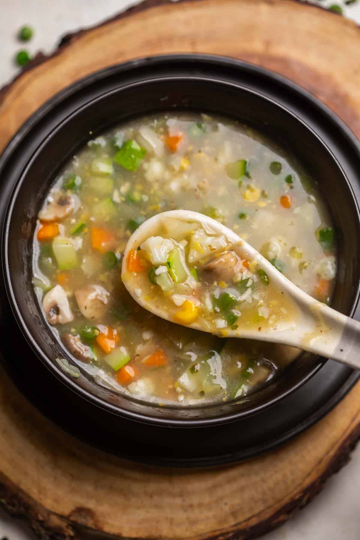 Eight treasure soup served in a black soup bowl with a white soup spoon ready to be eaten