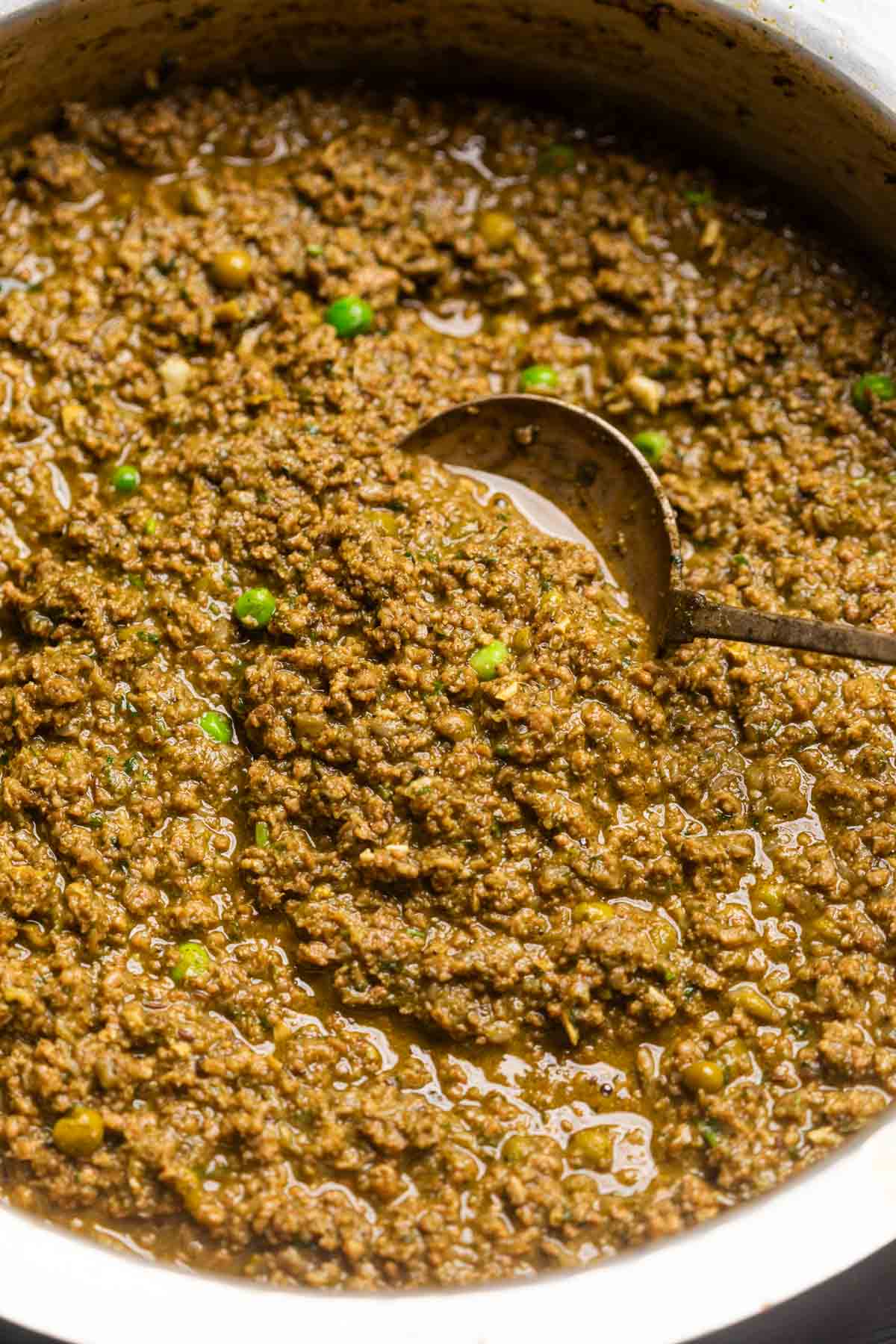 green keema masala in a copper kadai with a ladle