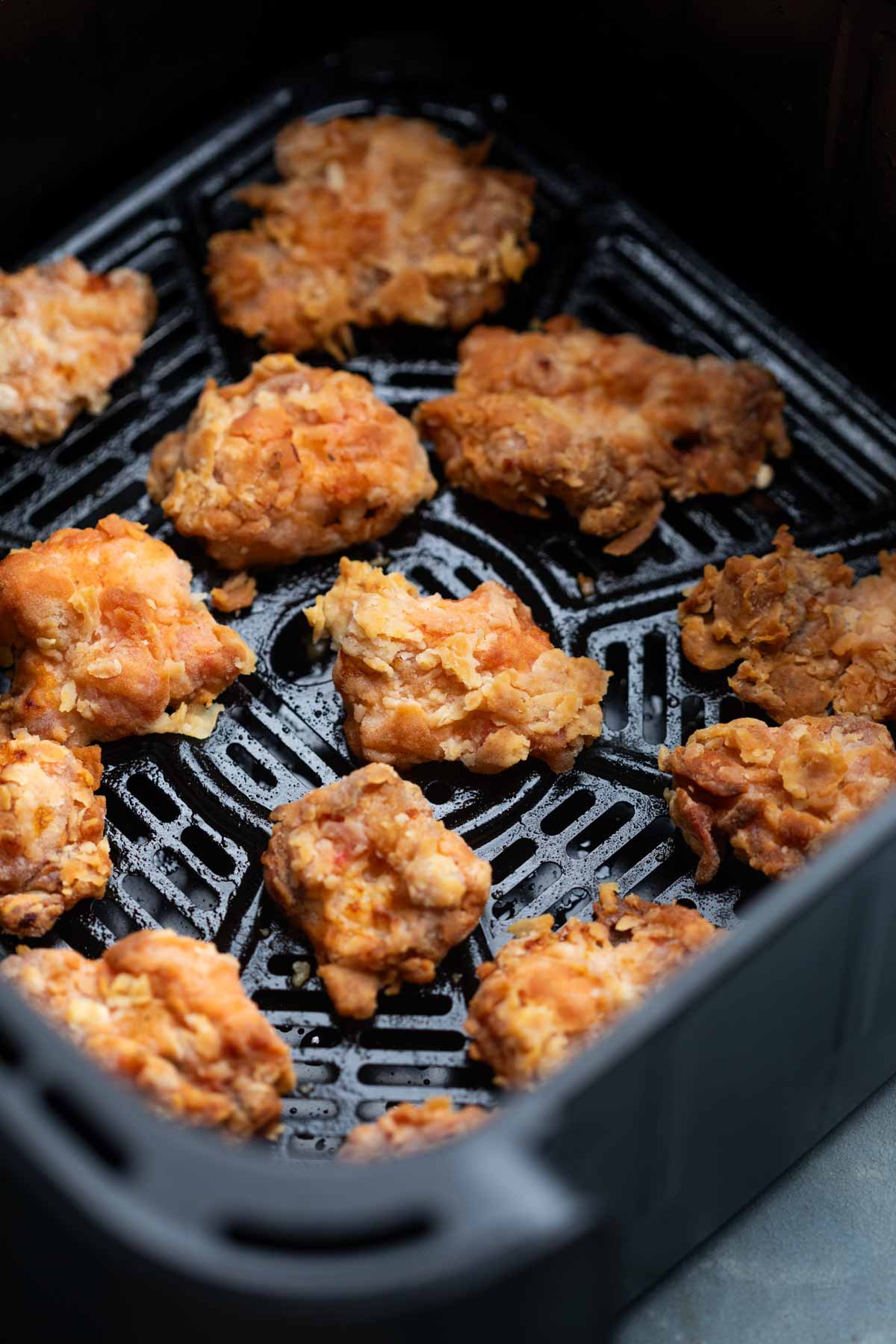 an image of air fried chicken pieces in an air fryer basket to showcase their crispy texture