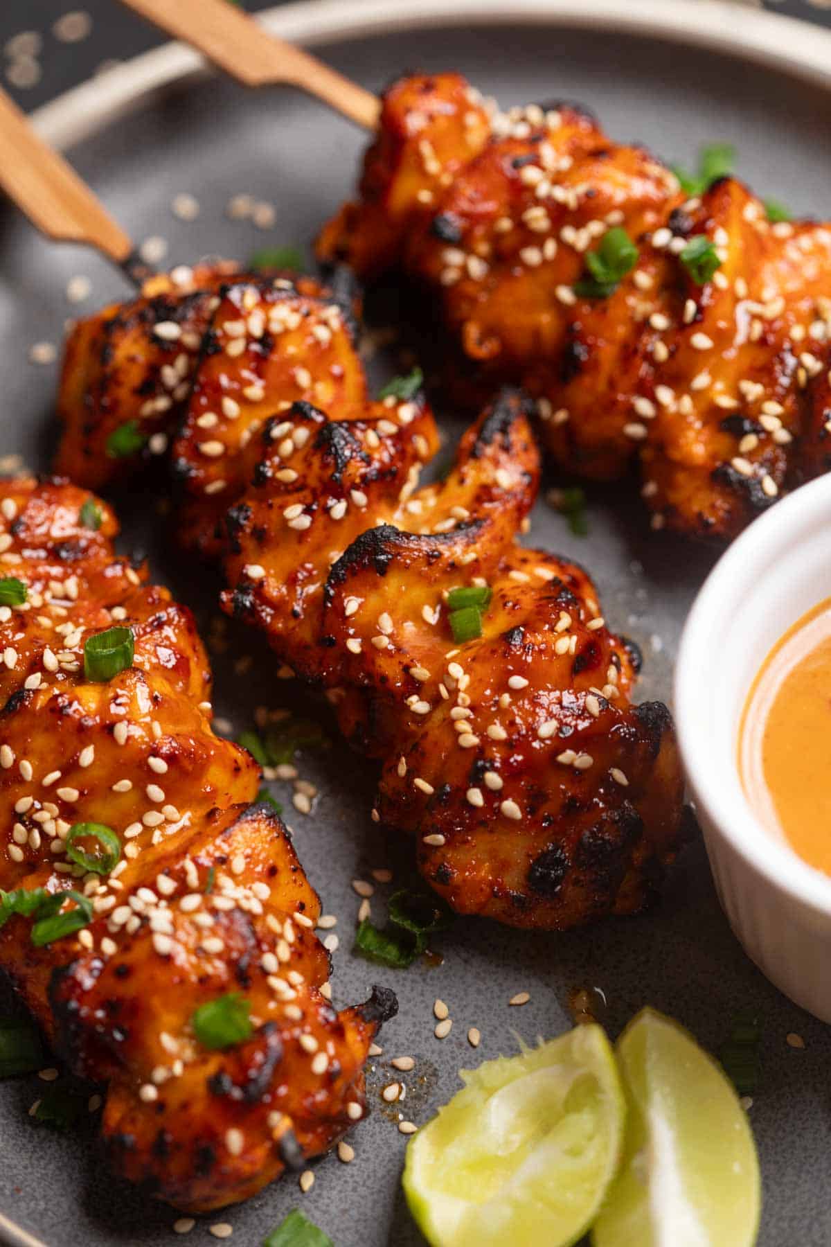 an image of bang bang chicken skewers served on a black platter with accompaniments