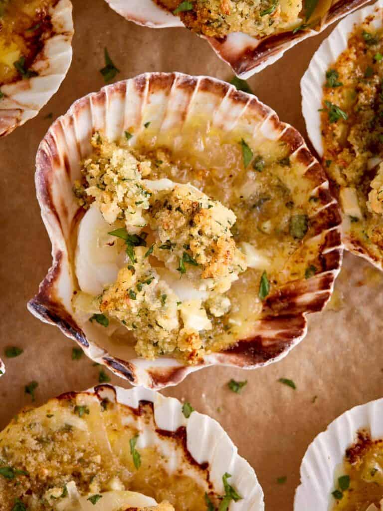 Baked scallops gratin served in their shells, topped with golden breadcrumbs, fresh parsley, and melted garlic butter.