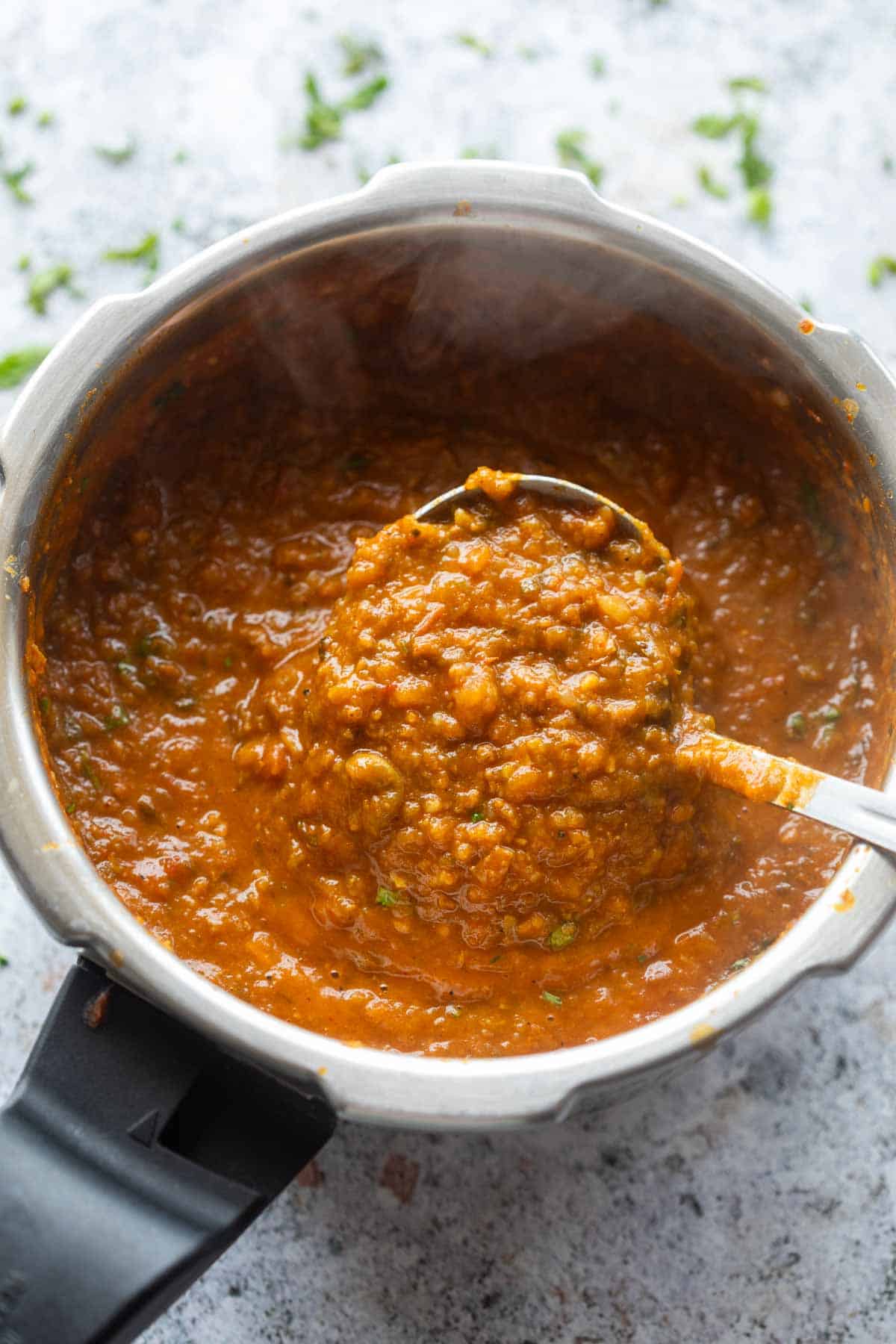 freshly made one pot pav bhaji scooped up in a ladle to show it's texture