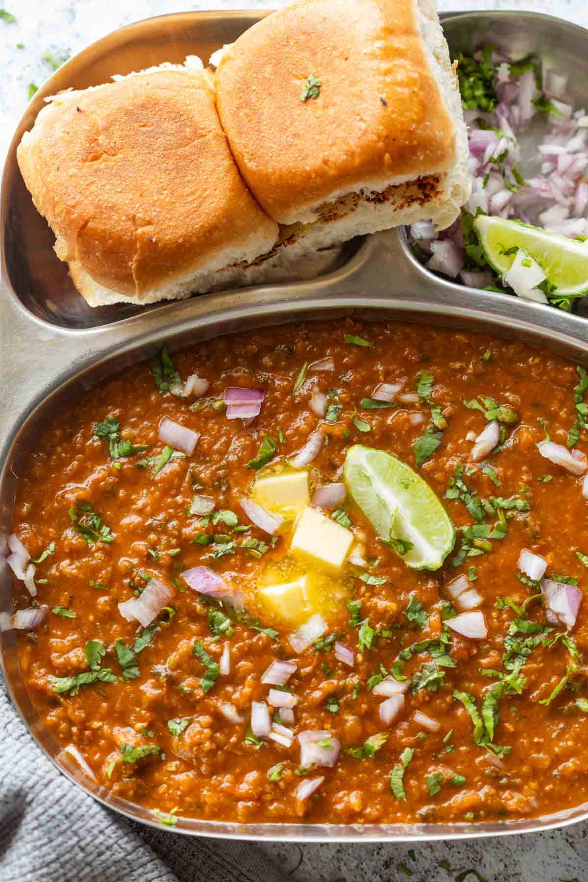pressure cooker pav bhaji served on a sectioned plate with accompaniments