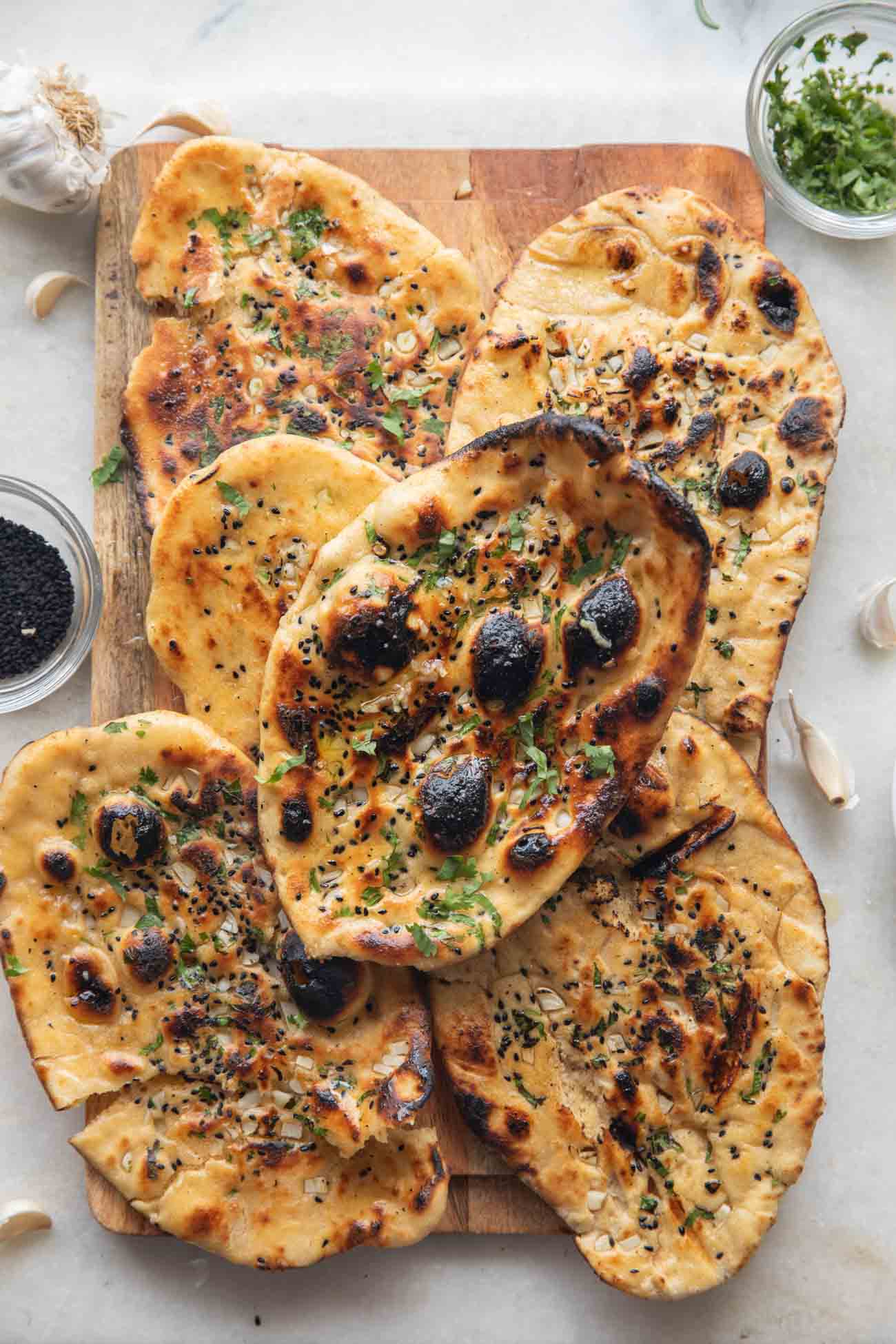image of butter garlic naan stacked one on top of the other on a wooden board