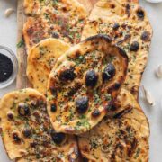 image of butter garlic naan stacked one on top of the other on a wooden board